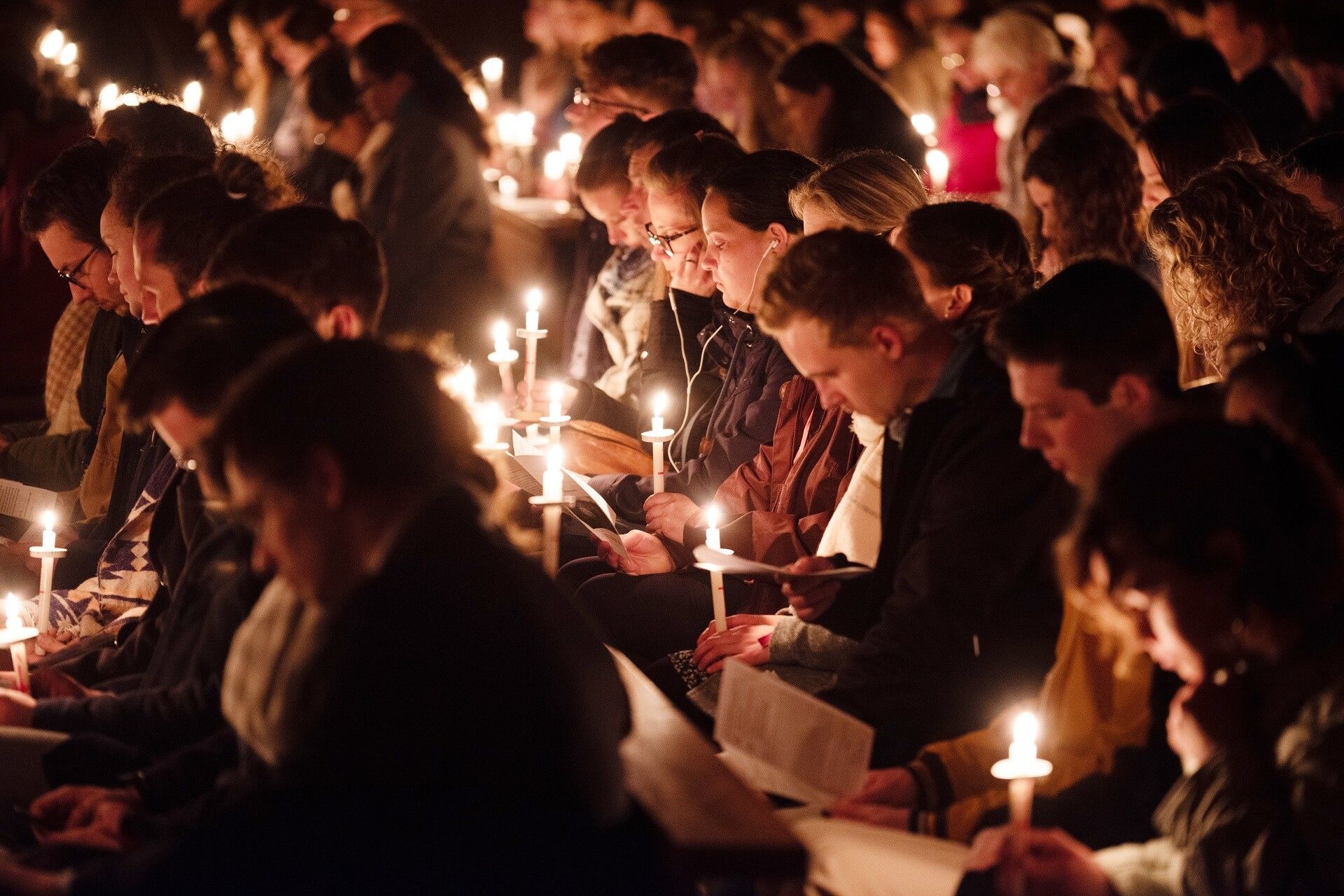 Young adults holding candles during a night vigil, faces lit by candlelight