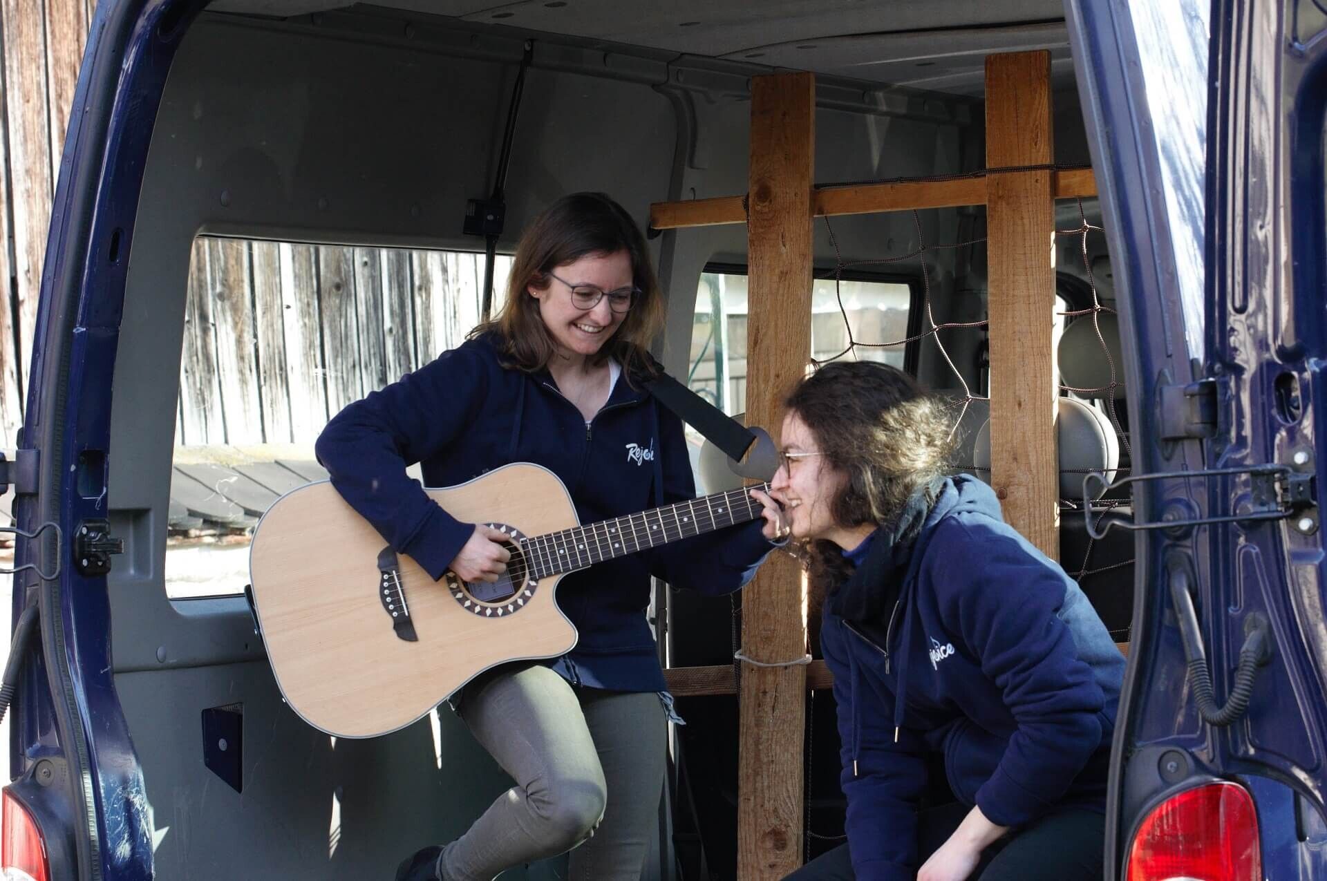 A missionary playing guitar in the open side door of the mission van